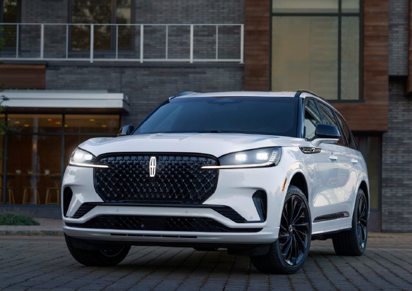 A 2026 Lincoln Aviator® Reserve model is shown with the available Jet Appearance Package parked near a restaurant. | Bondy's Lincoln in Dothan AL
