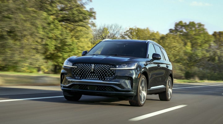 A 2026 Lincoln Black Label™ Aviator® SUV is being driven down a road lined with trees. | Bondy's Lincoln in Dothan AL