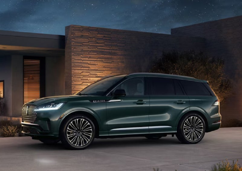 A green 2027 Lincoln Aviator® SUV is parked outside a contemporary home. | Bondy's Lincoln in Dothan AL