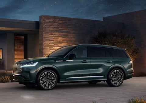 A green 2027 Lincoln Aviator® SUV is parked outside a contemporary home. | Bondy's Lincoln in Dothan AL