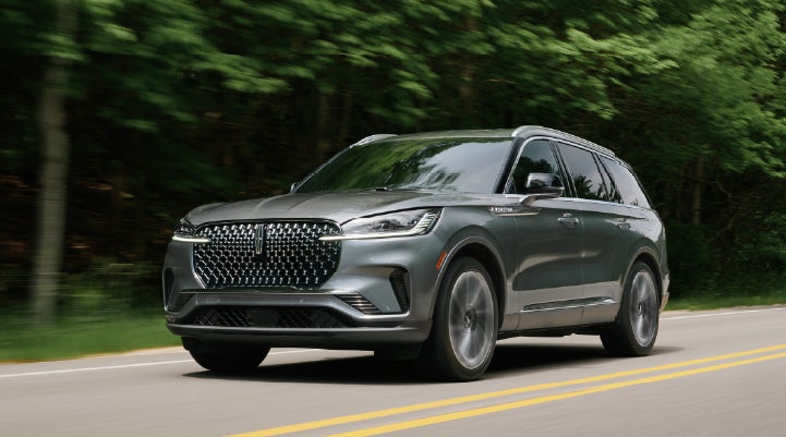 A 2027 Lincoln Aviator® SUV is being driven down a road lined with trees. | Bondy's Lincoln in Dothan AL