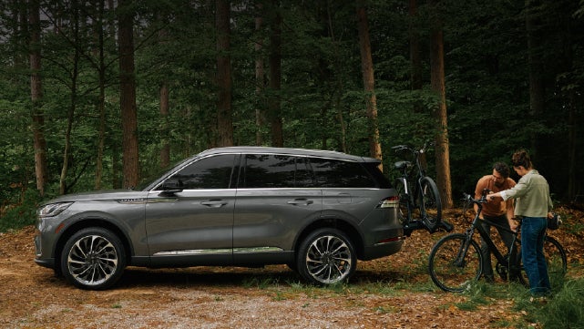A father and son load e-bikes on a bike rack attached to a 2027 Lincoln Aviator® SUV. | Bondy's Lincoln in Dothan AL