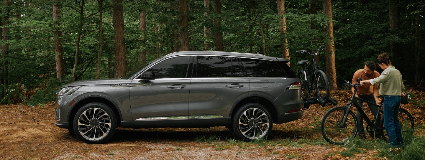 A father and son load e-bikes on a bike rack attached to a 2027 Lincoln Aviator® SUV. | Bondy's Lincoln in Dothan AL